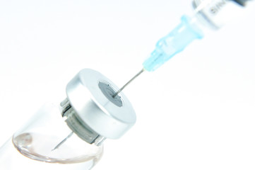 syringe needle in vial with vaccine