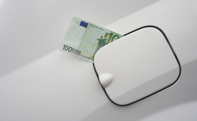 euro banknote in the fuel tank of car. concept of expensive gas