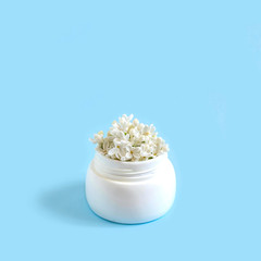 Jar with flowers of white lilac as cosmetic cream