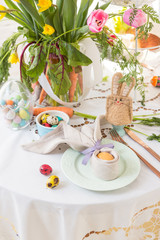 Painted egg wrapped in a linen napkin shaped like bunny ears on Easter breakfast table. Polish Easter