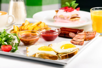 plate of breakfast food with bacon, eggs, toast, and fried potatoes