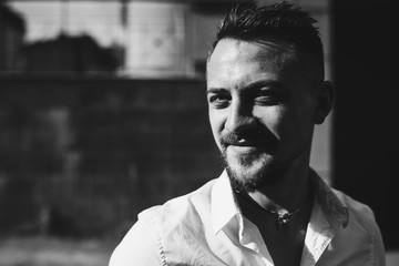 Close up portrait of young man in sunglasses in the streets outdoors posing next to the old building. Happy, fan, true emotions.