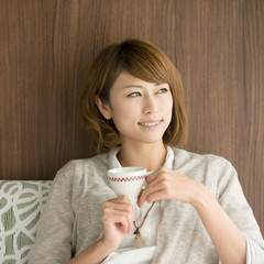 コーヒーカップを持ち微笑む女性