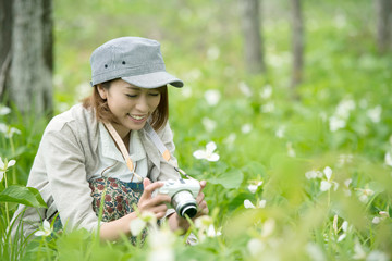 ミラーレス一眼カメラで植物の写真を撮る女性
