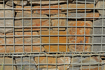 Zaun mit Gabionen und Steinen