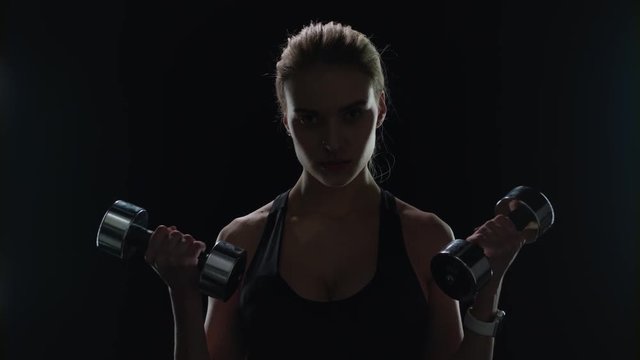 Fit woman training with dumbbells in slow motion. Strong girl lifting dumbbells