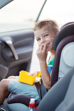 Happy little boy in the car eating cookies