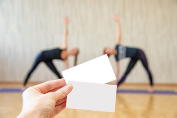 Two women practice yoga and on their background is a hand with a card.