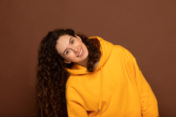 Portrait of beautiful cheerful brunette girl with flying curly hair smiling laughing looking at camera over brown background