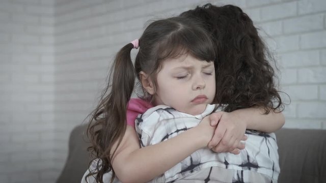 Depressed child hugs mother. Sad little girl hugging her mother.