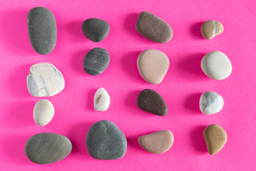 Obraz na płótnie Canvas granite smooth pebbles sea stones on pink background top view
