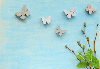 Springtime background with green leaves and wooden butterflies
