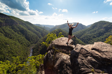 Obraz premium Spirited woman jumping on a high cliff ledge.