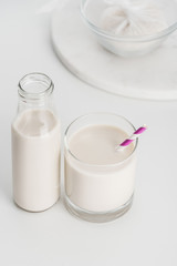 selective focus of rice milk in bottle and glass with rice in cheesecloth on background