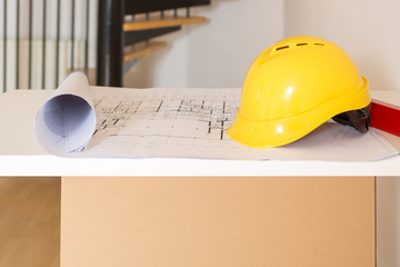 Utensilien für den Architekten auf einer Tischplatte: Bauskizze, Helm und Wasserwaage, closeup
