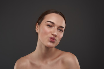 Cheerful young woman with natural makeup pouting lips