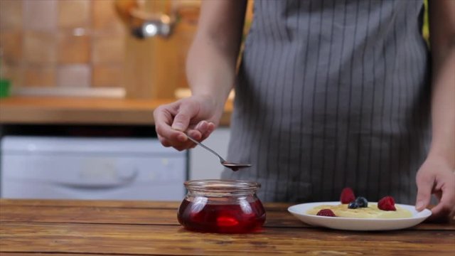 Woman pouring straberry sauce onto tasty homemade waffles, closeup