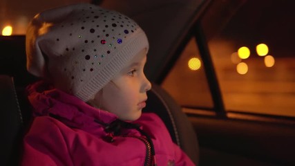 Little girl looks out of the car at night city