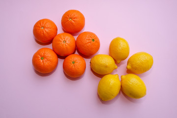 Fresh organic tangerines and yellow lemons on pink background, top view