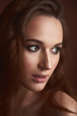 Fototapeta premium Gorgeous young woman with smoke eyes makeup posing against brown background