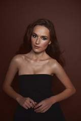 Naklejka premium Beautiful young woman in elegant black dress holding perfume