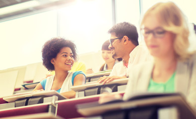 education, high school, university, learning and people concept - group of international students talking in lecture hall