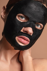 Portrait of the woman having black sheet mask on her face