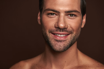 Portrait of happy attractive man isolated on brown