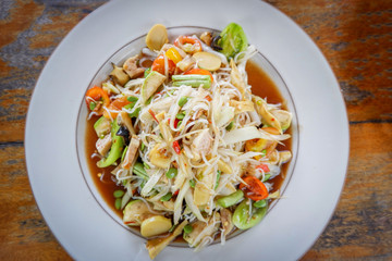 Green papaya salad spicy with rice noodle mix vegetable and fruit on white plate / Som tam thai food
