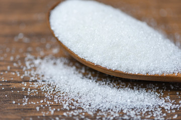Fototapeta na wymiar White sugar on wooden spoon and wood background