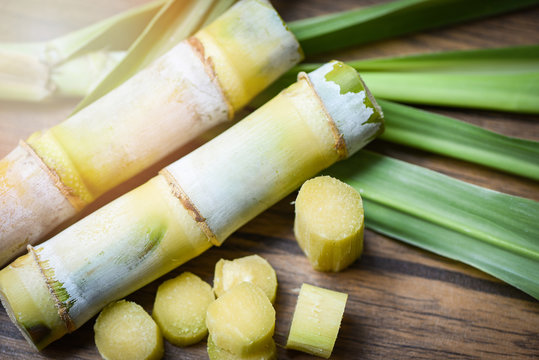 Sugar Cane And Green Of Leaf Cut Sugarcane Piece On Wooden Table Background