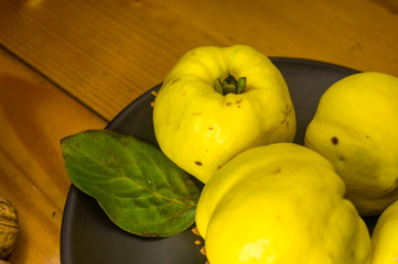 large yellow quince fruits on a ceramic plate, with anise, cinnamon, and walnuts