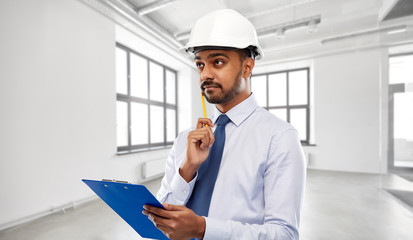 architecture, construction business and building - indian architect or businessman in helmet with clipboard thinking over empty room background