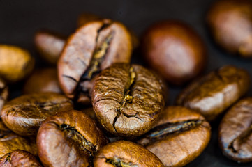 Brown roasted coffee beans on black background, close up, macro