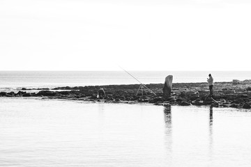fishermen on the seashore waiting for the catch of the day with their fishing rods