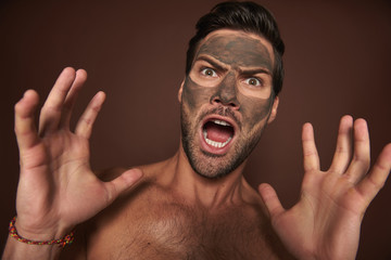 Scared excited muscular guy with face mask