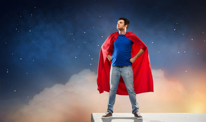 super power and people concept - happy young man in red superhero cape over starry night sky...