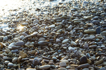 pebble stones on the sea beach, the rolling waves of the sea with foam