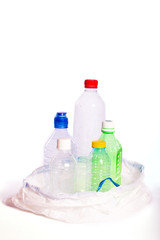 Plastic pollution. Some empty plastic bottles inside a white garbage bag, isolated on white background