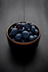 45 degree angle view of blueberries in a bowl and on dark grey