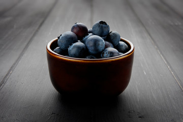 andscape shot of a 45 degree view of blueberries in a bowl and on dark grey