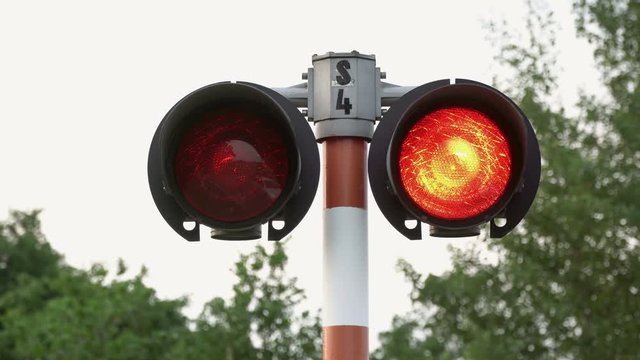 Two railway crossing signal pulsating in red. On the shot you can see a bright glow in the lens.