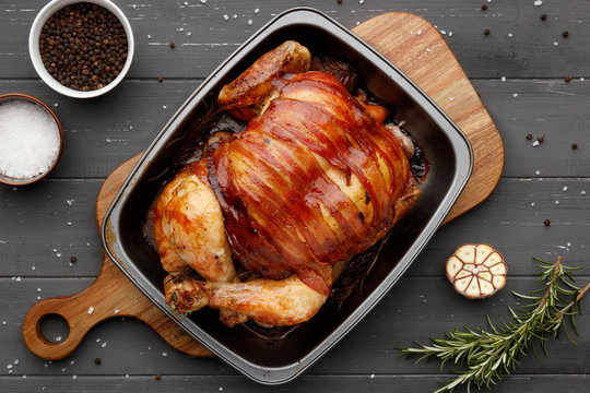 roast chicken in a rasting tin with ingredients on dark grey