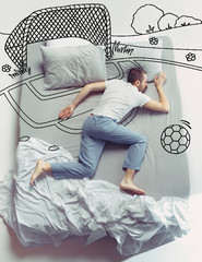 Missed football and childhood. Top view photo of young man sleeping in a big white bed at home....