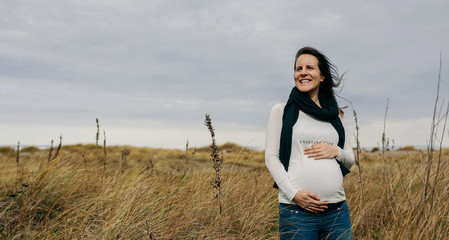 Pregnant woman caressing her tummy in the field