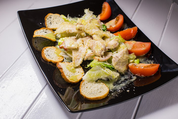 Caesar salad with bacon and quail eggs Black plate