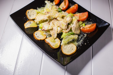 Caesar salad with bacon and quail eggs Black plate