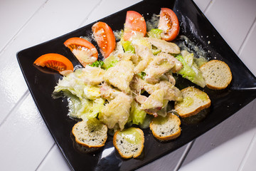 Caesar salad with bacon and quail eggs Black plate