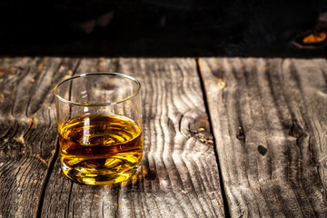 Elite drink for masculine relaxation. whiskey served on wooden planks. Vintage countertop with highlight and a glass of hard liquor. Free space for your text