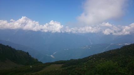 On the slope of a high mountain with a green slope and a top in clouds and fog. Sports and tourist base in the mountains. Krasnaya Polyana, Sochi, Russia.